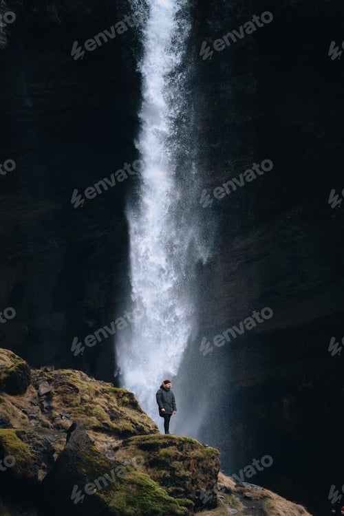 Preview: Person standing in front of a tall waterfall