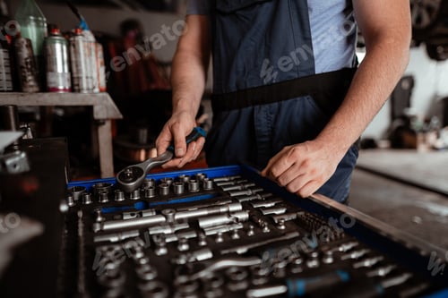 Preview: Mechanic organizing tools in a workshop while preparing for vehicle repairs