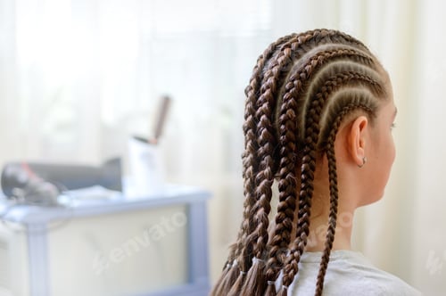 Preview: Girl in a hairdressing salon with a beautiful summer hairstyle in African style.