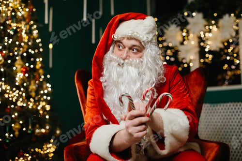 Preview: Santa claus holding candy canes near christmas tree