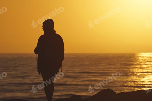 Preview: Listening to music while standing on the rocks on the ocean during the golden hour