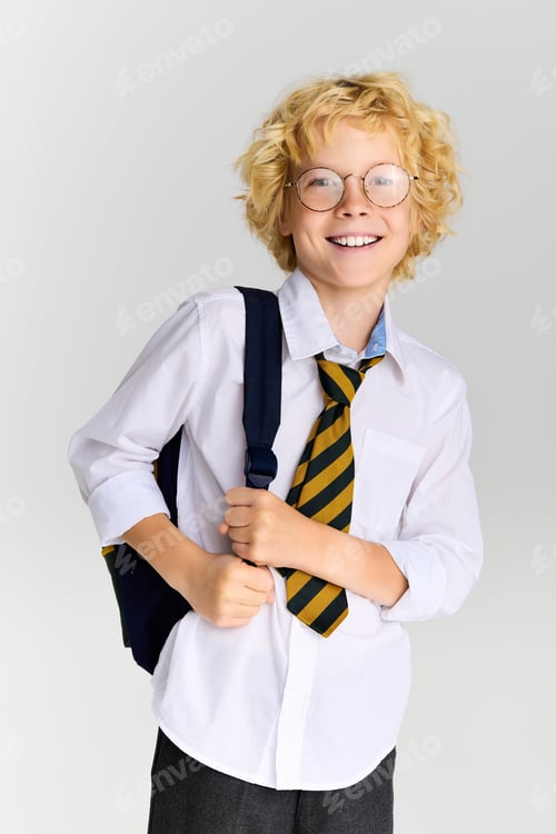 Preview: Blonde boy in school uniform smiles brightly in studio setting