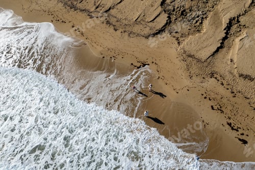Preview: Aerial drone point of view of people walking on sand in a beach. Stormy waves idyllic beach