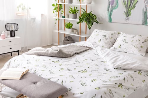 Preview: Green plant pattern on white bedding and pillows on a bed in a n