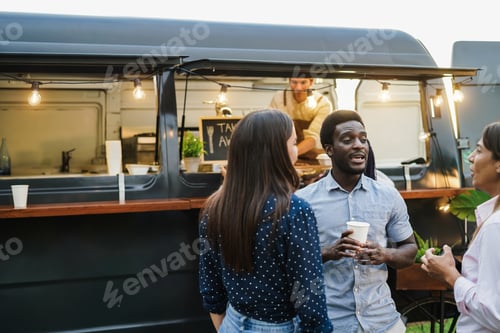 Preview: Multiracial people having fun drinking in front of food truck outdoor - Focus on african man face