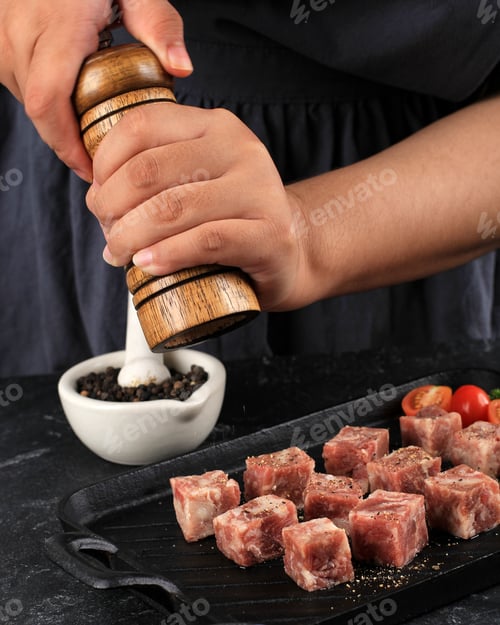 Preview: A Woman Cooks with Salt and Black Pepper Fresh Raw Saikoro Diced Steaks