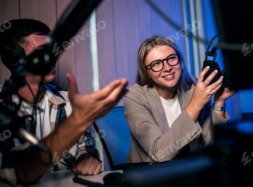 Preview: Young woman and man editing audio podcast in their studio.