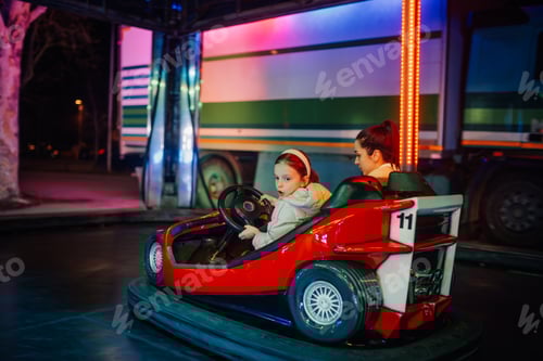 Preview: Little girl and mother having fun on a bumper car at the amusement park