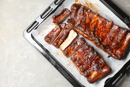 Preview: Delicious spare ribs on grey textured table, top view. Space for text