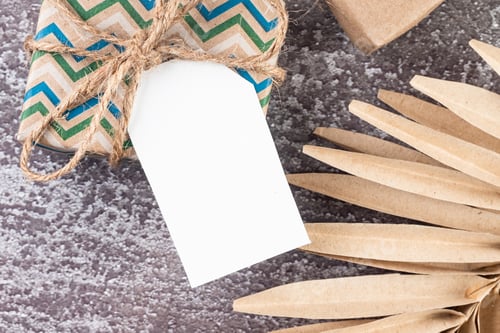 Preview: Empty white tag with gifts and Christmas decor on dark conkrete background.