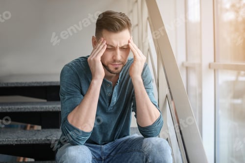 Preview: Man suffering from headache near window in office