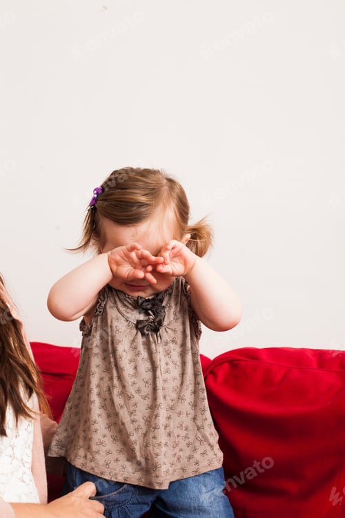 Preview: Baby girl rubbing eyes while crying at home