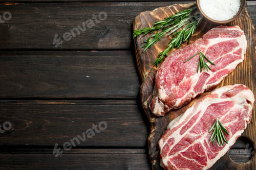 Preview: Raw pork steaks with rosemary.