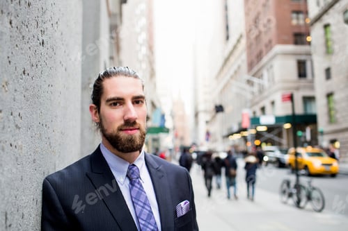 Preview: Portrait of young businessman leaning on wall in city