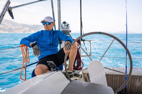 Preview: Young man captain stands at the helm and controls a sailboat during a journey by sea