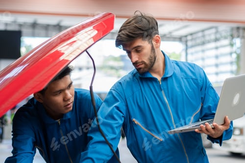 Preview: Car mechanic team using laptop boosting car engine at auto repair shop