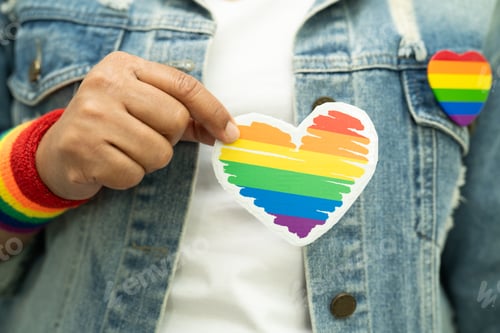 Preview: Asian lady wearing rainbow flag wristbands and hold red heart