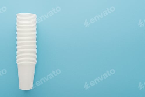 Preview: top view of white plastic cups on blue background with copy space