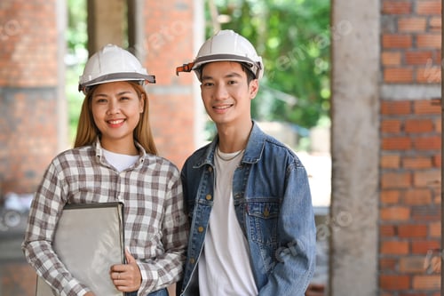 Preview: Two young architect standing with arm crossed at building construction site.