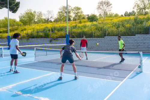 Preview: Four multi-ethnic friends playing pickleball in an outdoor court