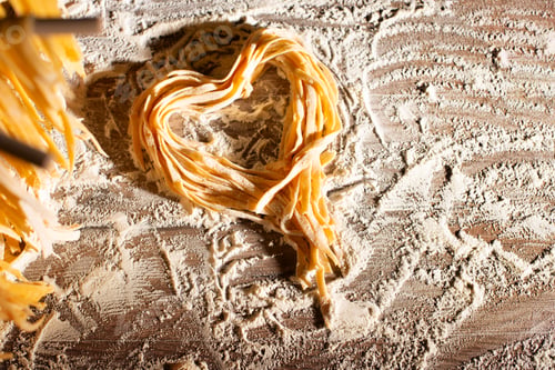 Preview: Heart shaped noodles on floured kitchen table top view