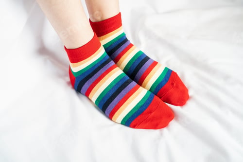 Preview: Women's legs in socks colors alternating, side stand on white fabric floor.