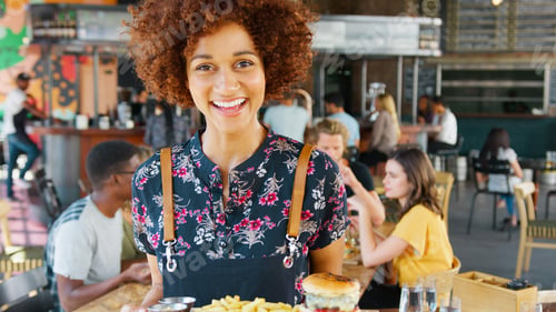 Preview: Portrait Of Female Server In Busy Bar Restaurant Smiling At Camera