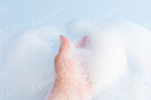 Preview: Woman's hand in delicate white foam cosmetics, bath foam, shower gel, soap. The concept of SPA