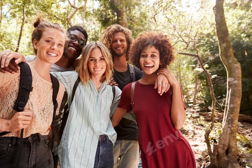 Preview: Five young adult friends hiking in a forest smiling to camera, three quarter length, close up