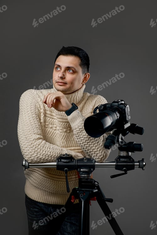 Preview: photographer in sweater near digital camera on tripod