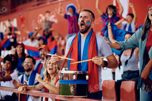 Preview: Passionate sports fan playing drums during a match at the stadium.