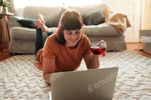 Preview: Shot of a woman using her laptop while relaxing at home