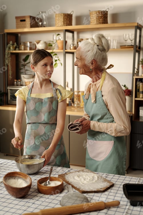 Preview: Senior Caucasian Woman Teaching Teenage Girl Baking in Kitchen Together