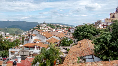 Preview: Beautiful view of Taxco with traditional architecture and lush mountains under a blue sky