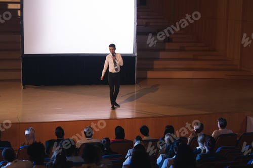 Preview: Businessman standing and giving presentation in auditorium in auditorium