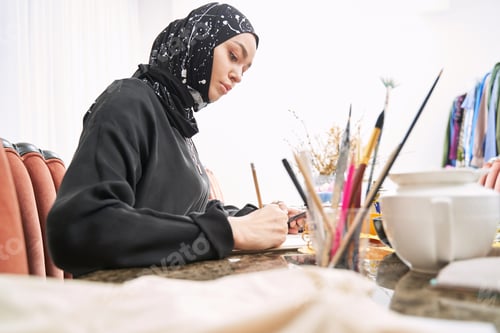 Preview: Muslim female designer creating clothes in sketchbook