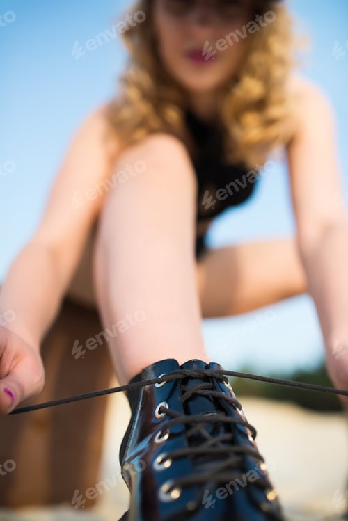 Preview: Blurred beautiful young girl tying shoelaces in a black underwear