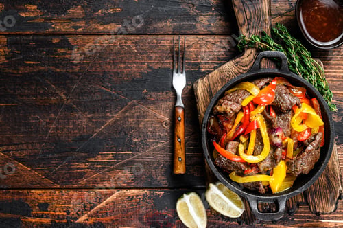 Preview: Fajitas beef meat traditional Mexican food dish in a pan. Dark wooden background.
