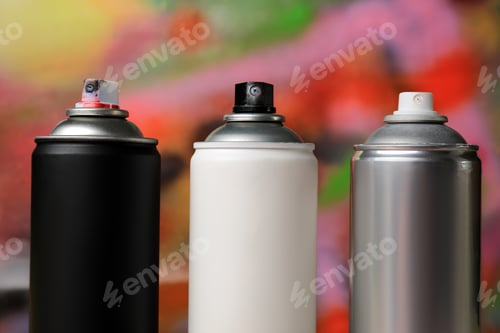 Preview: Cans of different graffiti spray paints on color background, closeup