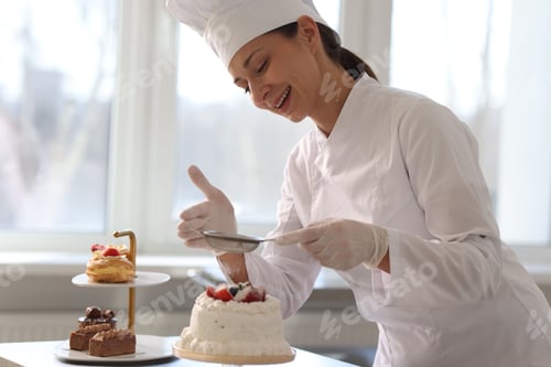 Preview: Confectioner sprinkling powdered sugar onto cake in kitchen