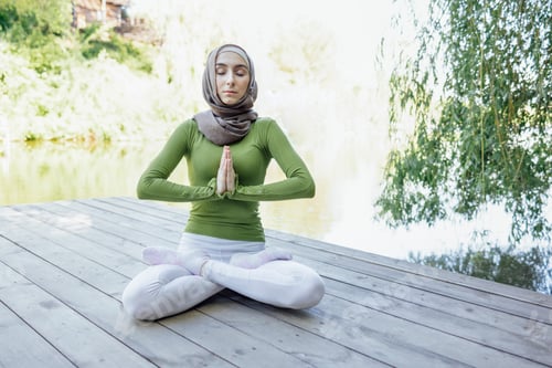 Preview: Muslim young girl in a hijab is doing yoga asana in the park