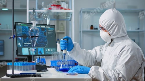 Preview: Chemist wearing ppe suit putting liquid in test tube with micropipette