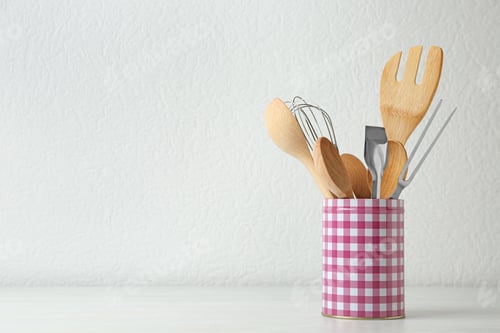 Preview: Set of kitchen utensils in stand on wooden table near light wall. Space for text