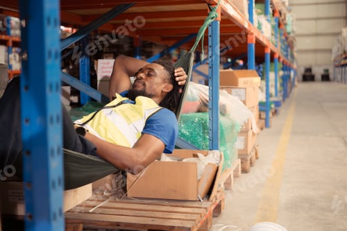 Preview: Portrait of happy mature African American man relaxing in hammock in warehouse