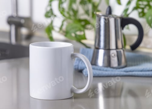 Preview: White coffee mug on grey kitchen table against moka pot and green plant closeup, mockup