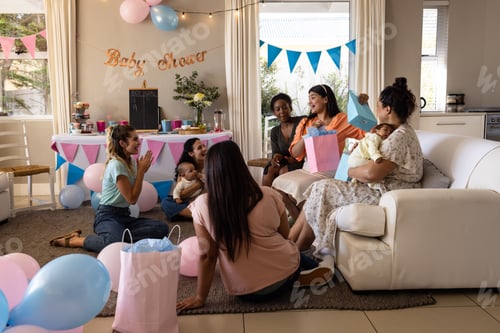 Preview: Women celebrating baby shower at home, exchanging gifts and enjoying conversation