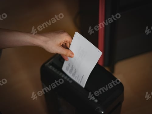 Preview: Hands of a ccaucasian young man is destroying documents in a black shredder