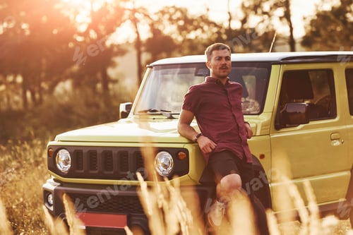 Preview: Portrait of man that leaning on green car at beautiful sunny day outdoors in the field
