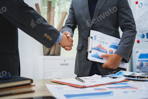 Preview: Asian business team in formal suits shakes hands at a meeting, symbolizing agreement.