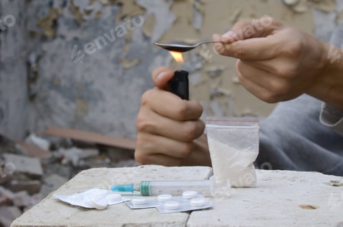 Preview: Hands of drug addict melting cocaine in a spoon holds over a cigarette lighter